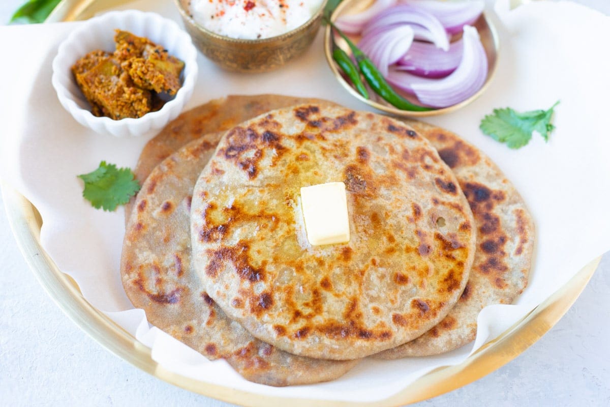 Homemade Aloo paratha garnished with cilantro and served with yogurt on the side