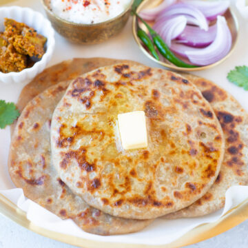 delicious Aloo Paratha stacked in a plate with butter