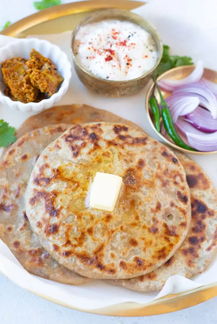 Piping hot Aloo Paratha served in a plate with onions