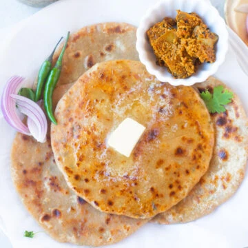 four paneer paratha in a plate with pickle on the side