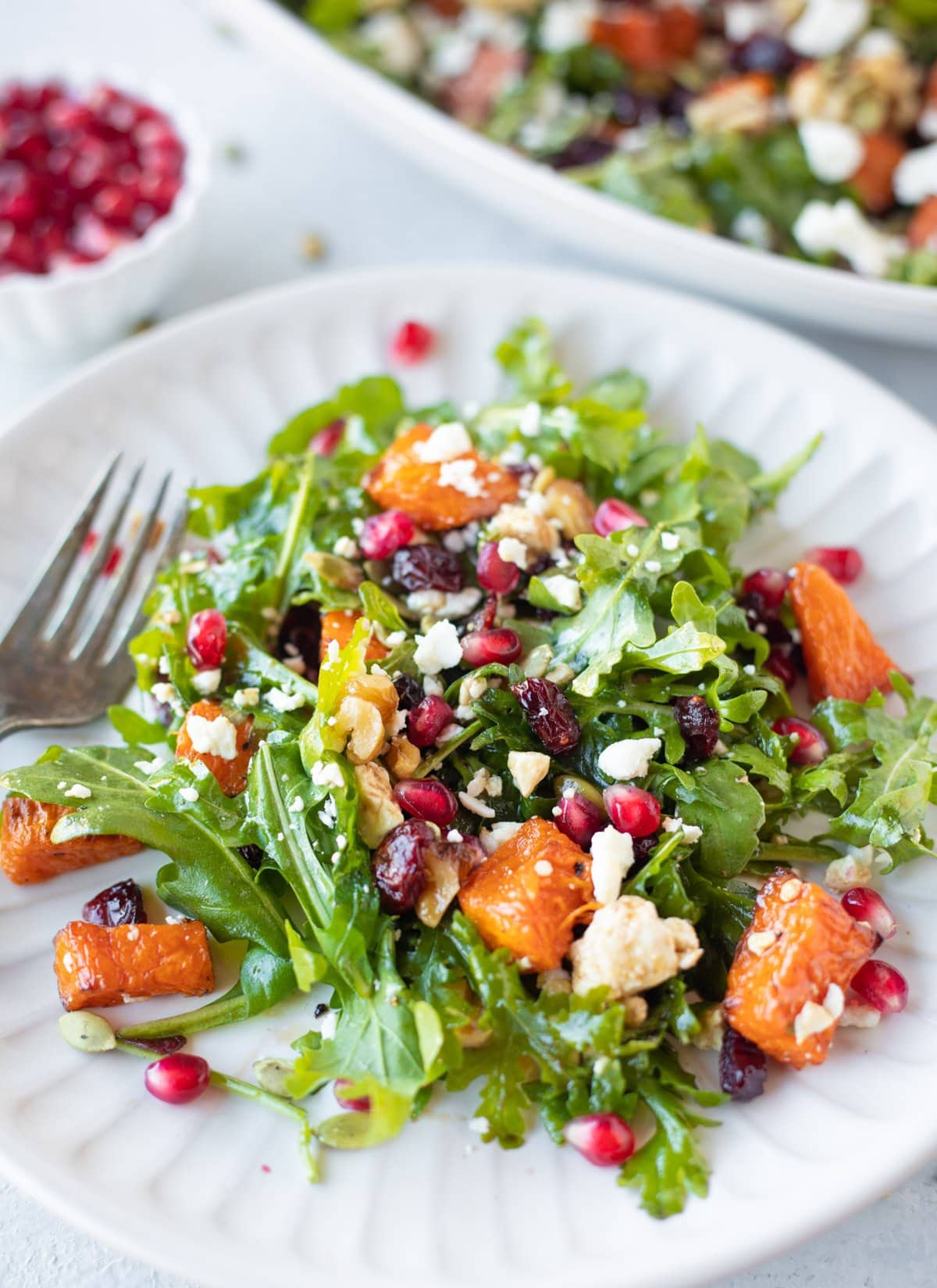 Gluten free pumpkin salad garnished with pomegranate and walnuts