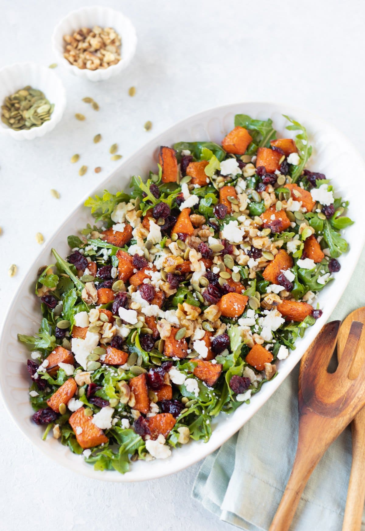 pumpkin salad in a white bowl with mixing spoon on the side