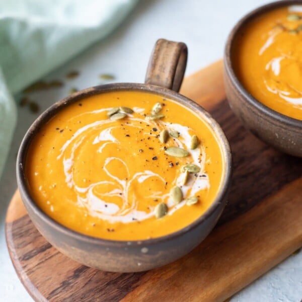 Roasted pumpkin soup in a rusty soup bowl topped with cream and pumpkin seeds