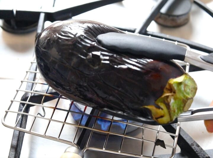 roasting eggplant on stovetop and turning with tongs 