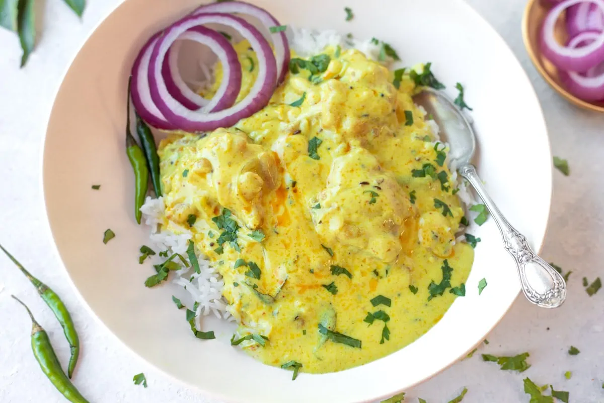 kadhi in a plate with onion on the side