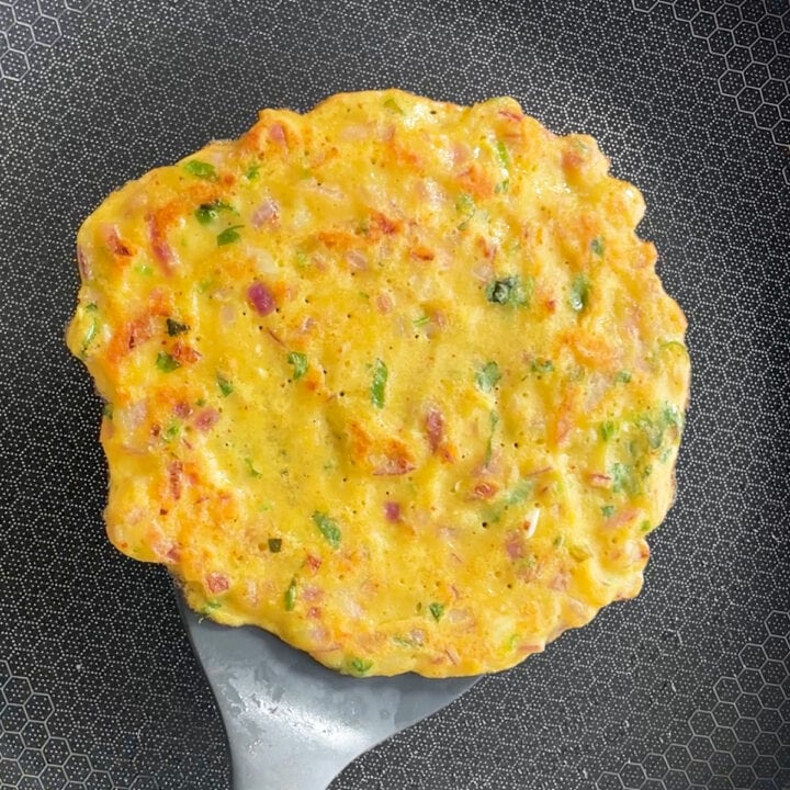 Cooked Moong Dal Chilla in a pan