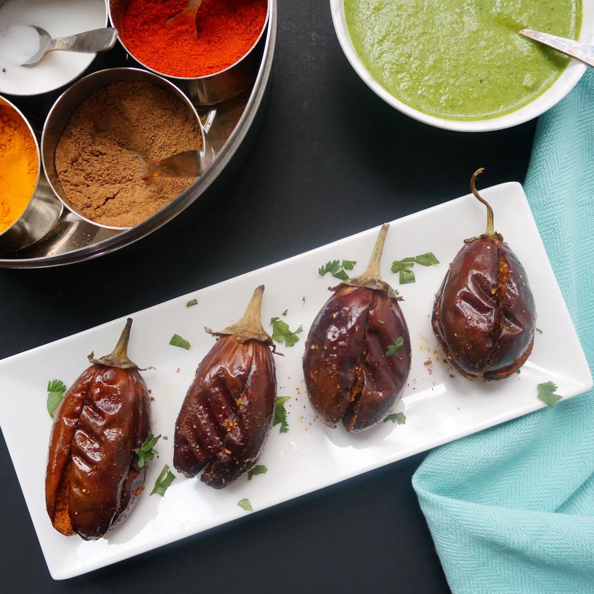 Stuffed Eggplant, also called Bharwa Baingan, served on a tray with chutney on the side.