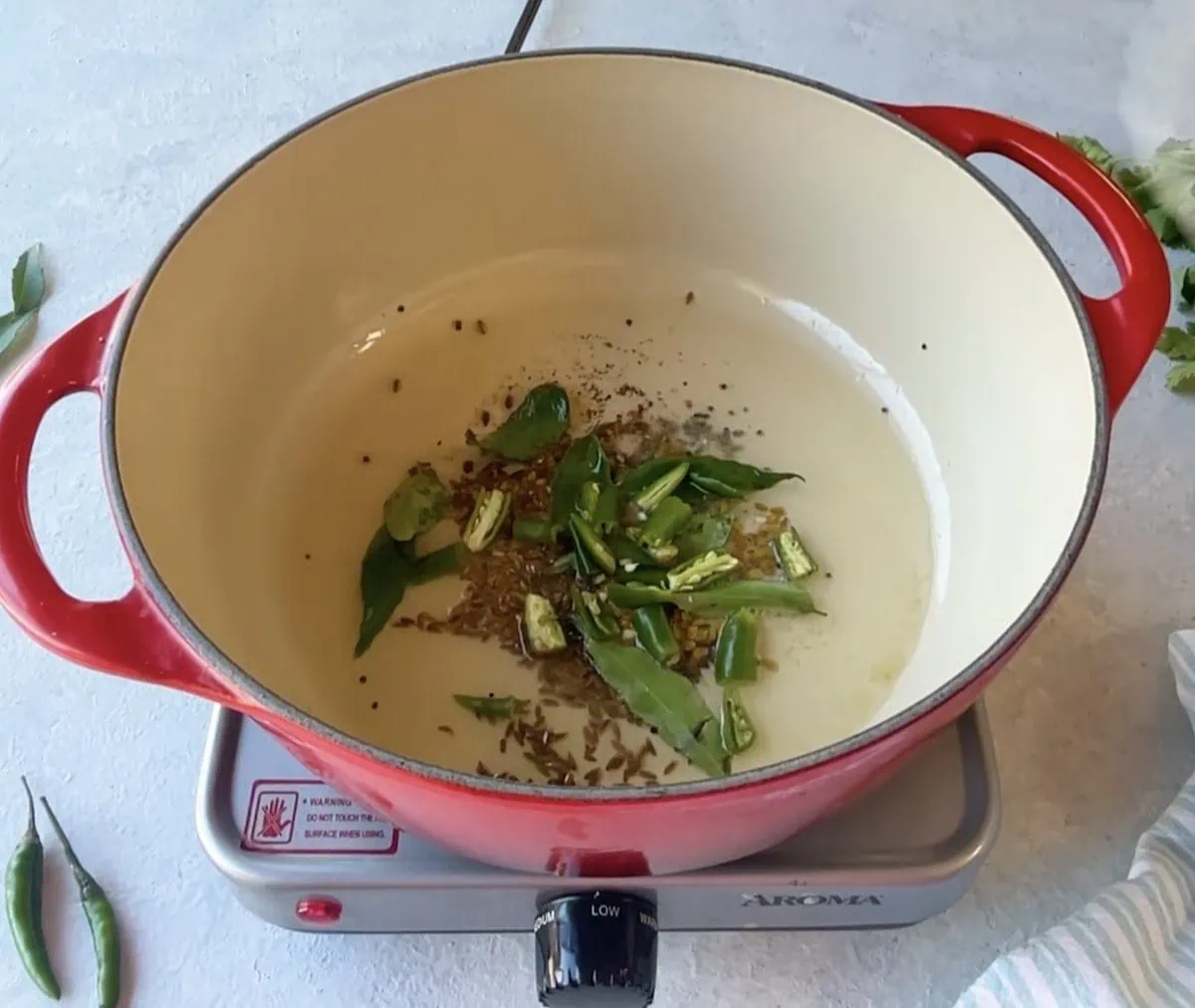 Tempering such as curry leaves, cumin seeds, green chili in a pot 