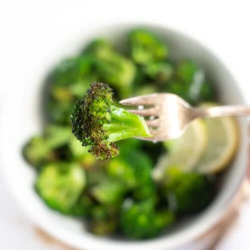Crispy air fried broccoli in fork over a bowl.