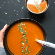 Roasted Carrot and Red Pepper Soup in a bowl garnished with sesame seeds and cilantro