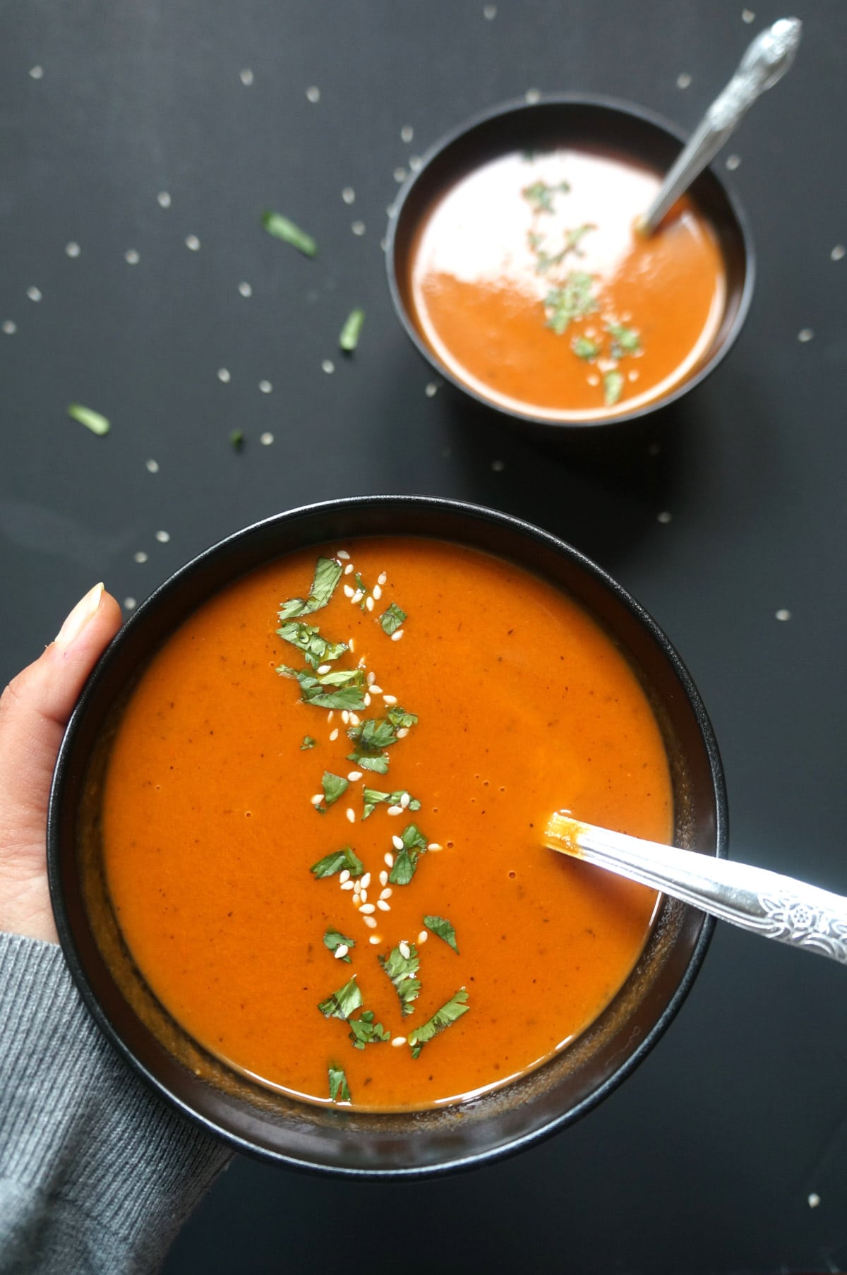Roasted Carrot and Red Pepper Soup in a bowl garnished with sesame seeds and cilantro