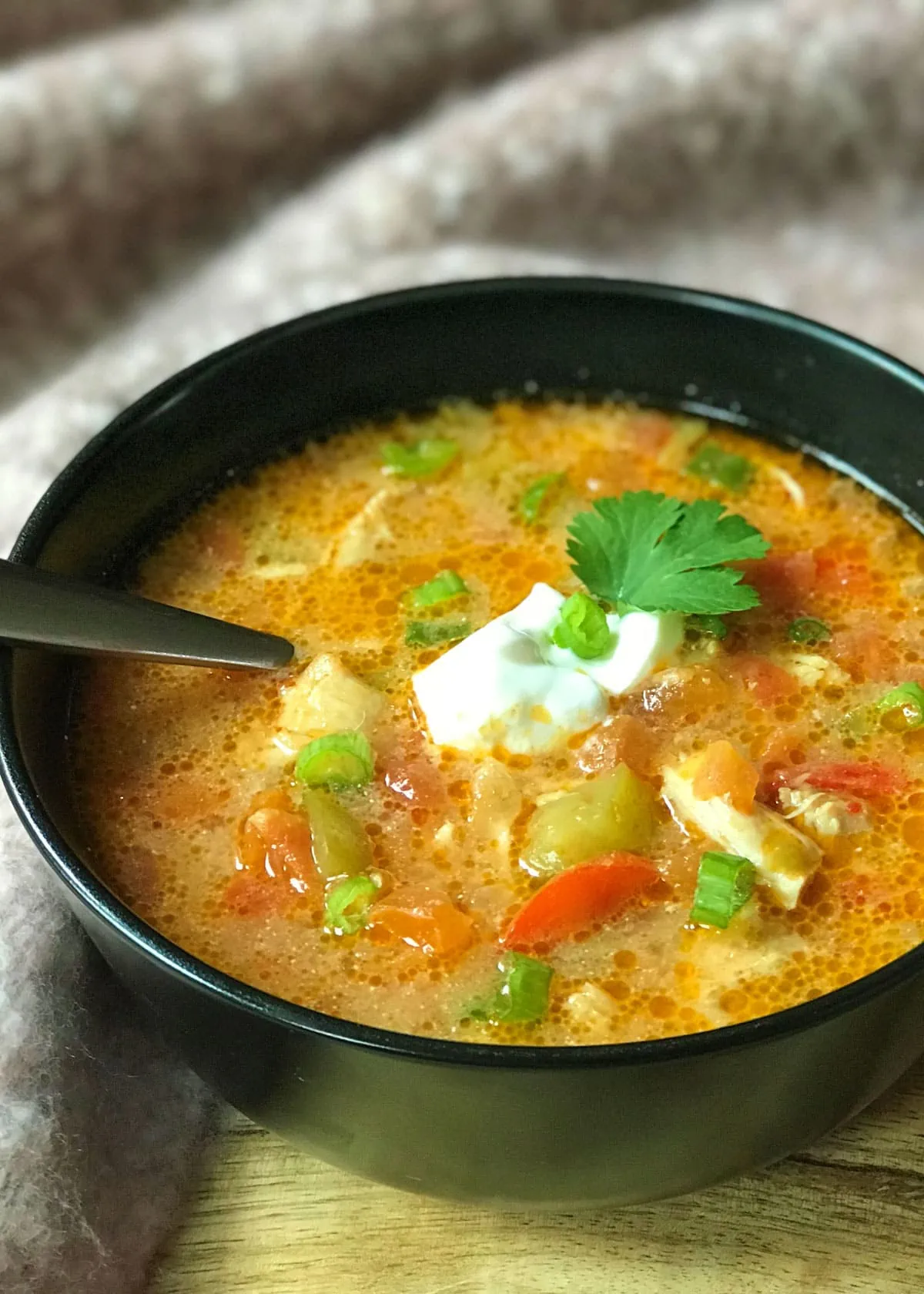 Chicken fajita soup served in a bowl topped with sour cream