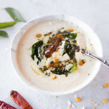 Coconut Chutney in a white bowl topped with tadka