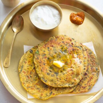 methi paratha in a brass plate with dahi