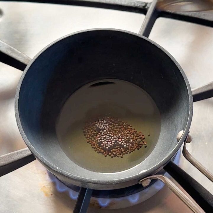 Making tempering with mustard seeds in a tarka pan