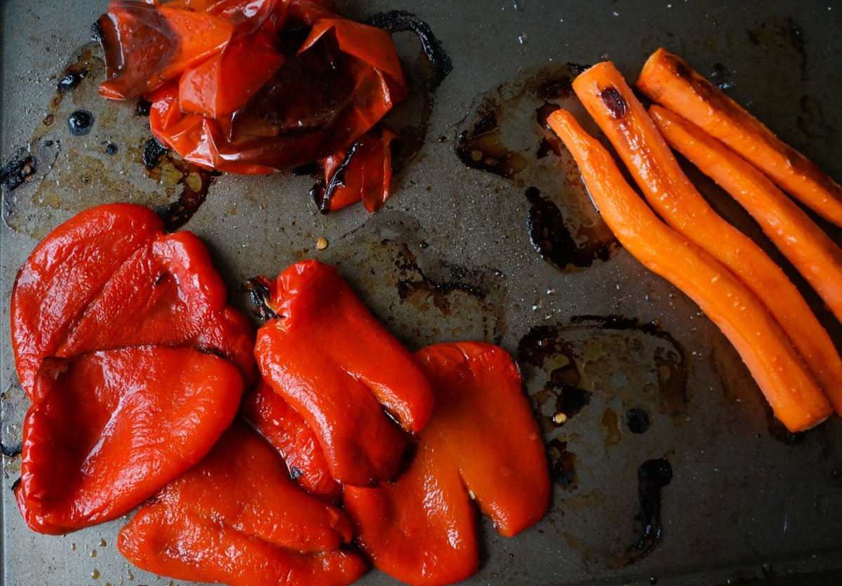 Roasted Carrots and peeled roasted red peppers on a baking tray