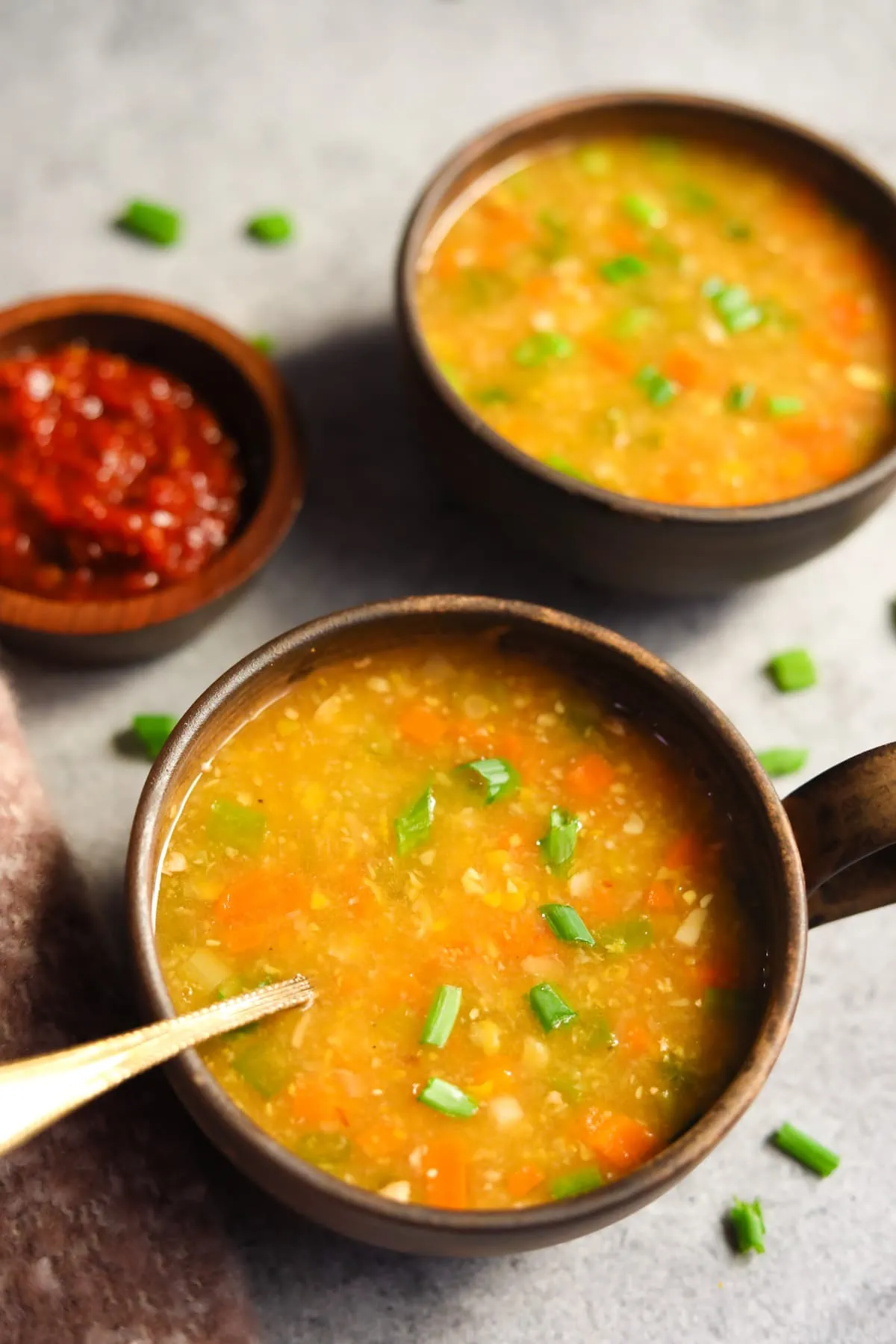 Delicious sweet corn soup topped with green onions served in two bowls.