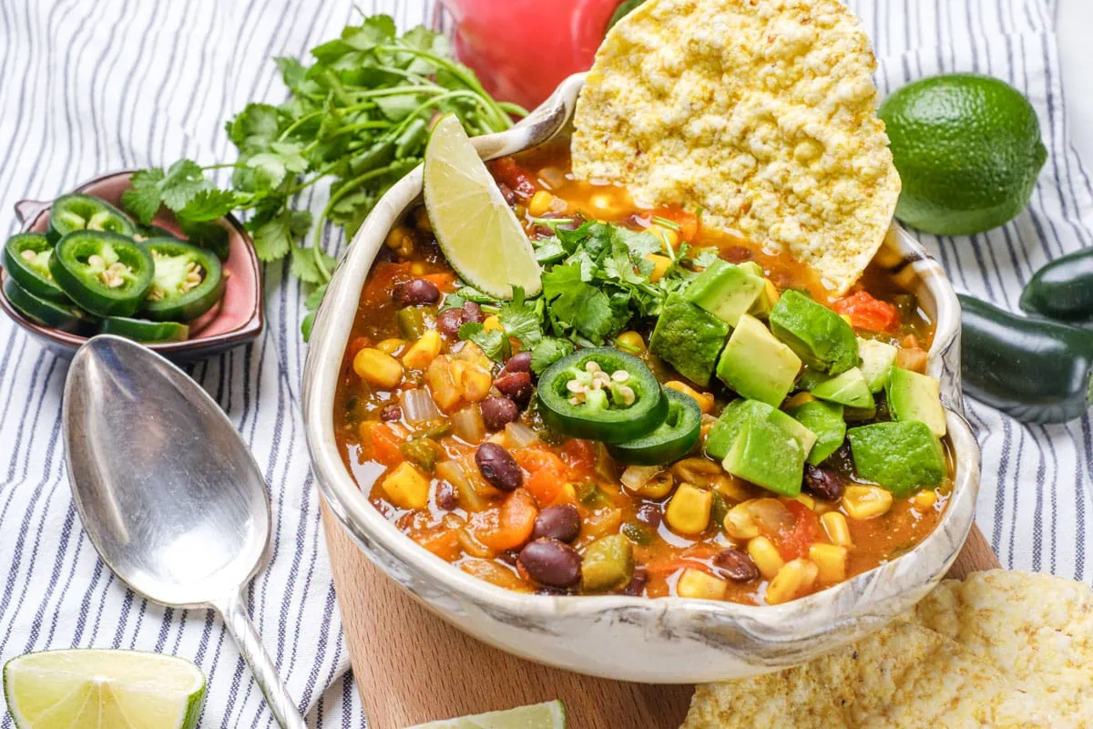 vegan taco soup in a bowl topped with avocado, cilantro, and jalapeños