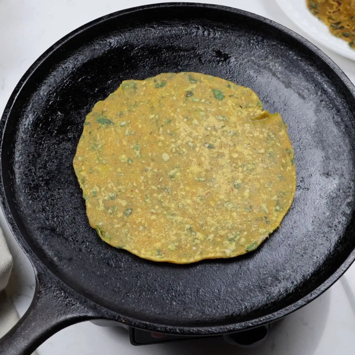 Flip methi thepla on cast iron tawa