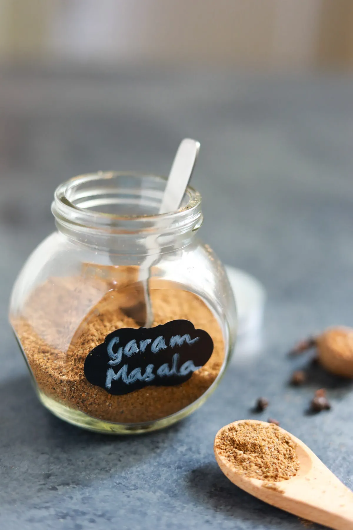Punjabi garam masala seasoning in a glass container and in a spoon.
