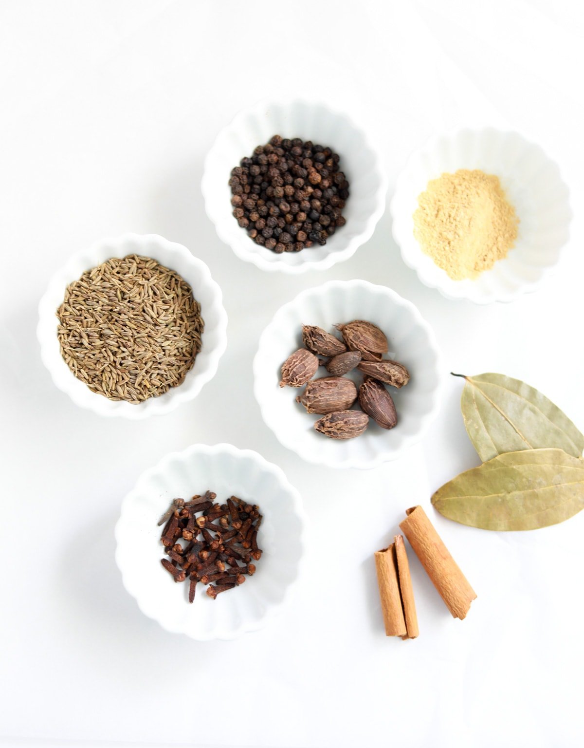 Whole spices in small bowls to make garam masala spice blend