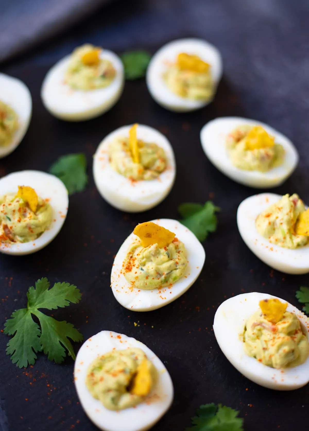 Guacamole deviled eggs on a platter with garnish of cilantro