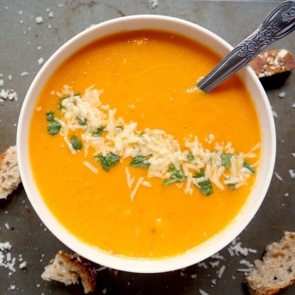Creamy tomato soup in a white bowl garnished with shredded cheese