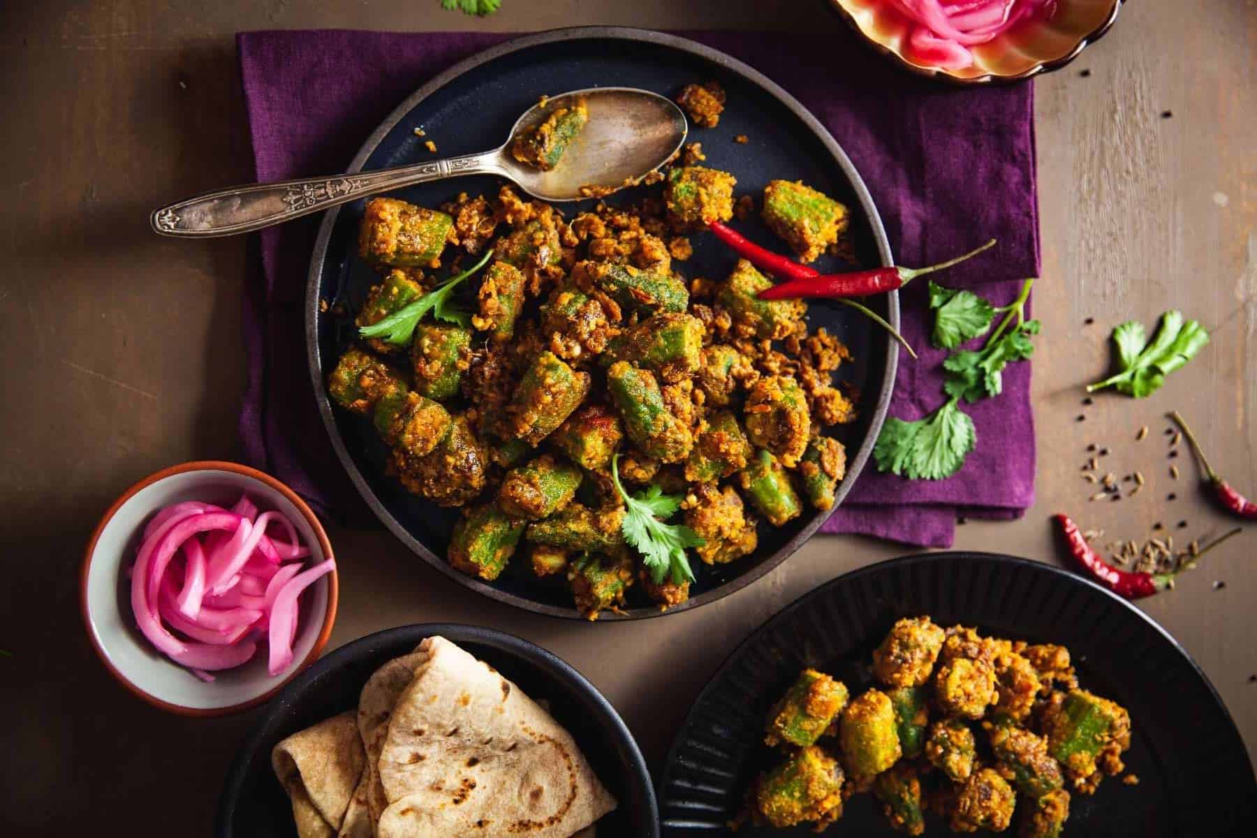 Besan Bhindi in a plate with roti and onions on the side.