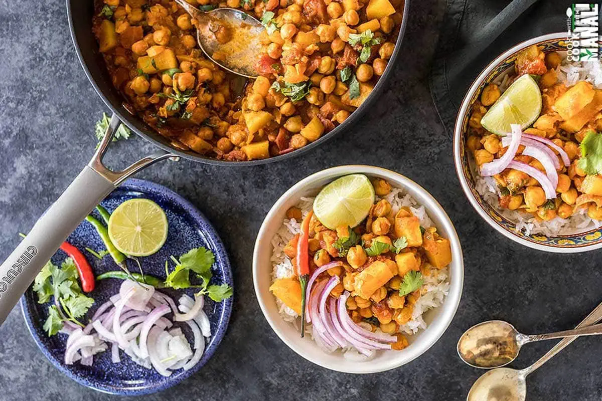 chana aloo served in 2 white bowls and topped with sliced onion and lime wedge