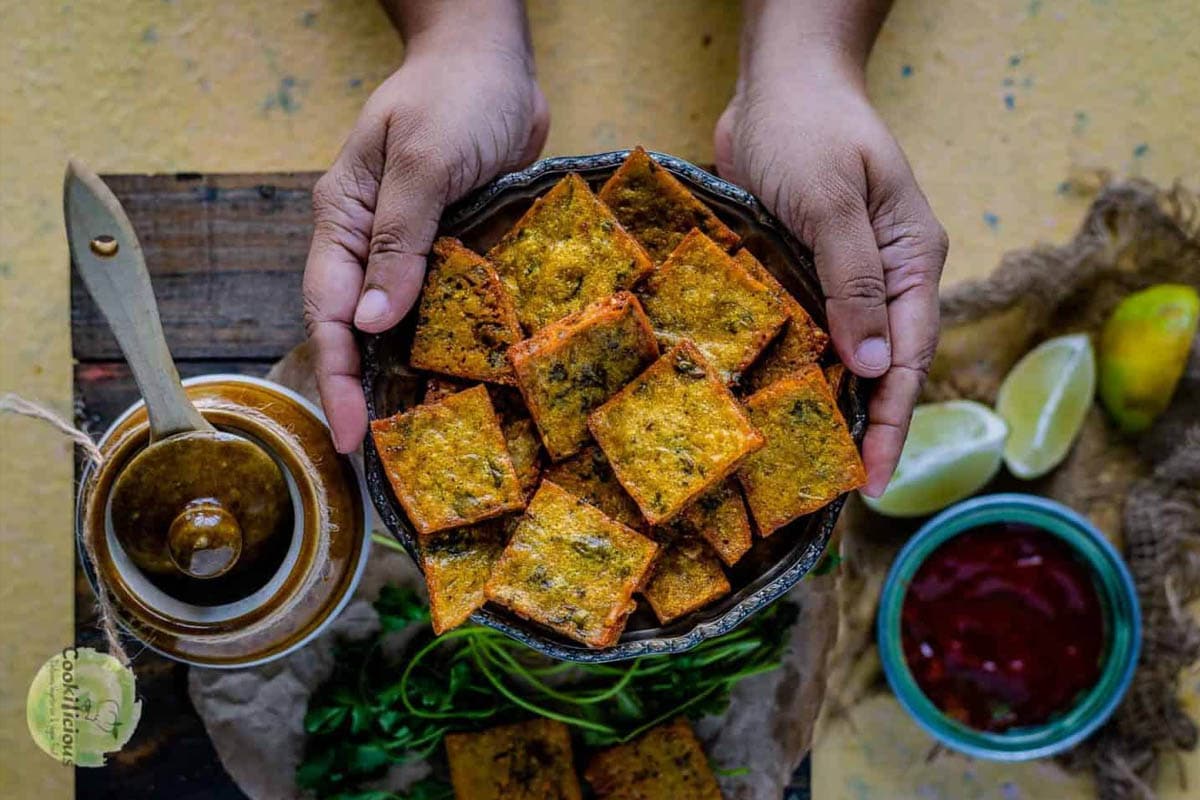 a set of hands holding a platter full of fried Vegan Cabbage Fritters