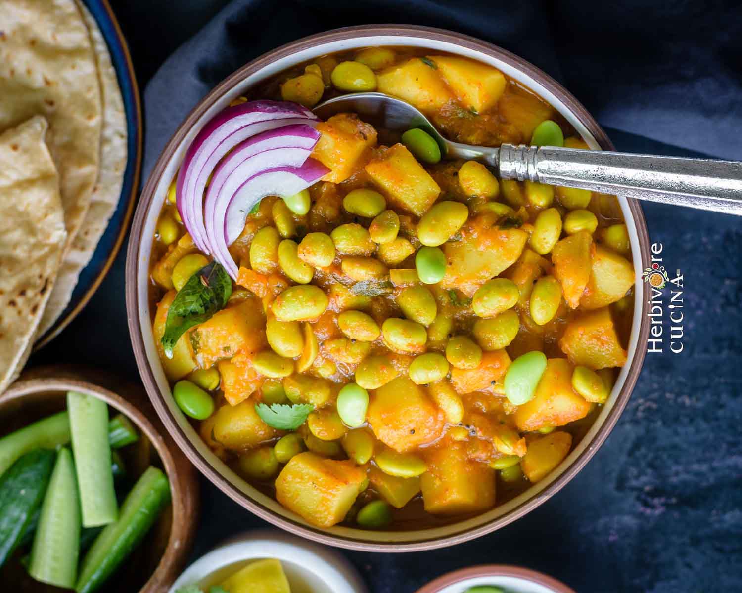 edmame and potato curry in a bowl topped with red onions 