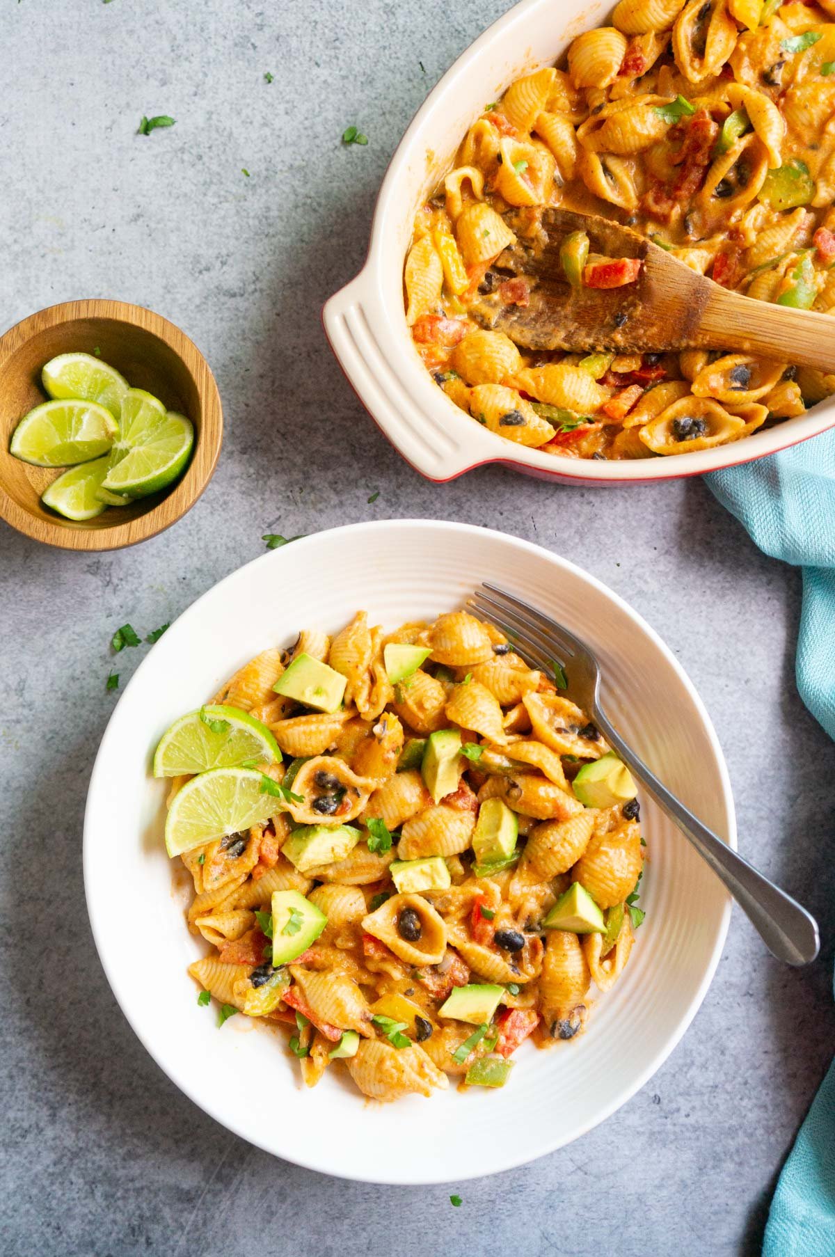 Fajita pasta in a bowl topped with avocado and lime wedges. 