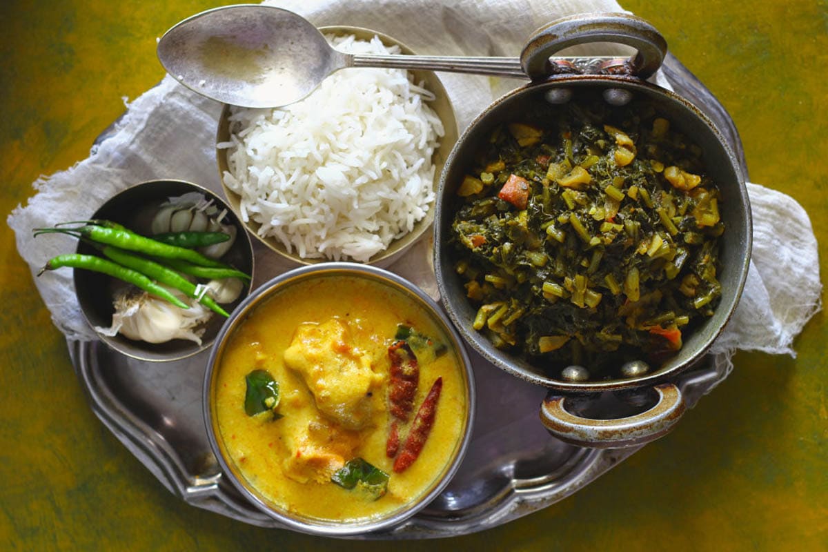 aerial shot of Indian thali meal with Kadhi Pakora, Mooli Ka Saag, Basmati Rice, Green Chili