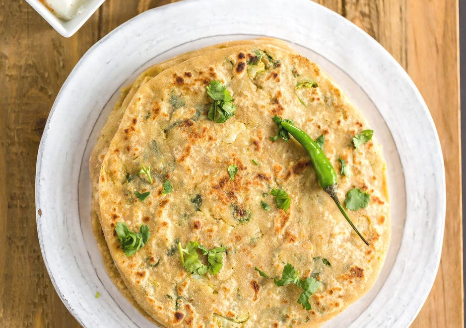 Gobi paratha in a plate topped with a green chili pepper 