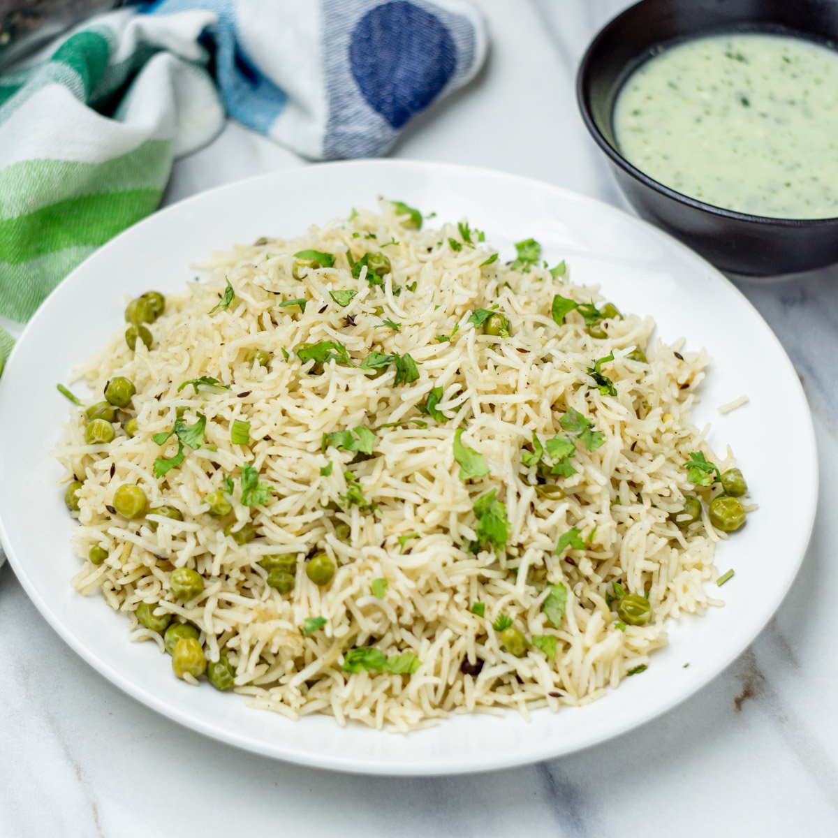 A flavorful and fragrant rice dish filled with green peas, and whole spices, and topped with chopped cilantro.