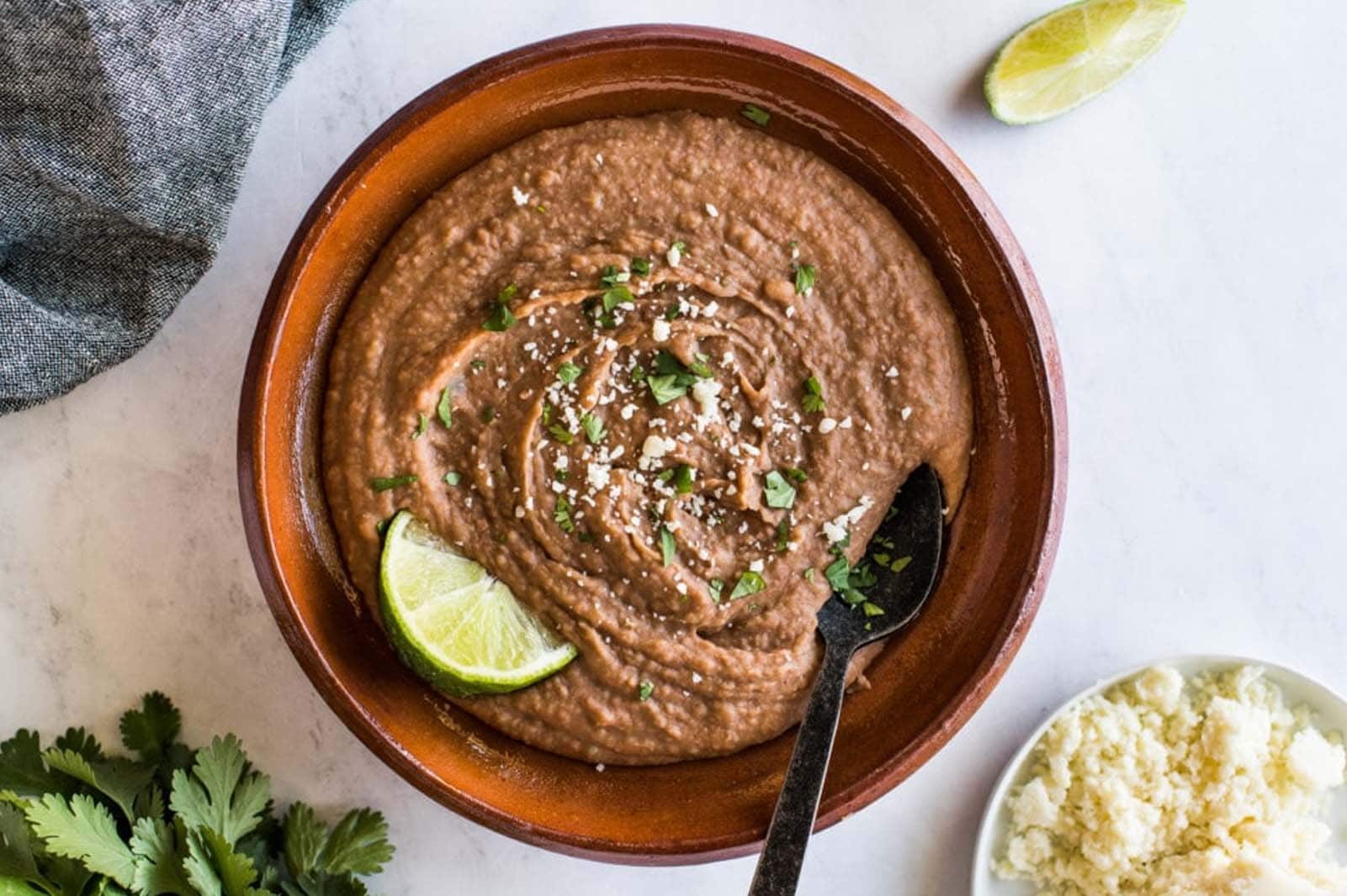 Instant Pot refried beans in a bowl topped with cilantro and cotija cheese.