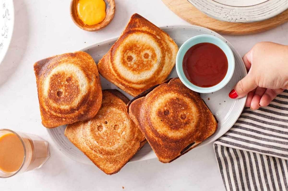 Potato Sandwiches served with ketchup on a oval platter with chai (tea). 