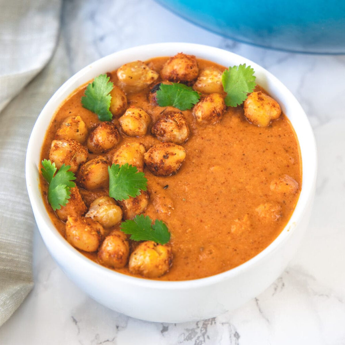 chickpea tikka masala in a bowl garnished with cilantro and napkin on the side.