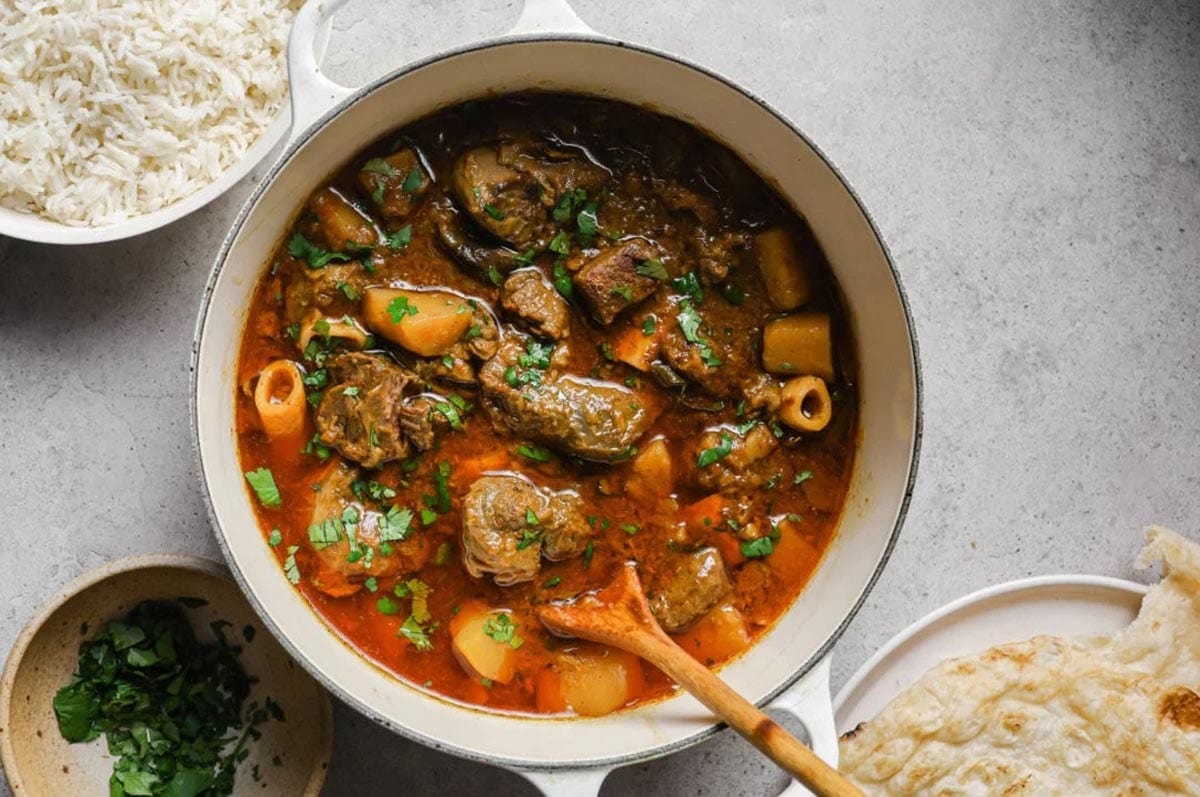 Aloo Gosht (Mutton and Potato Curry) in a white Dutch Oven.