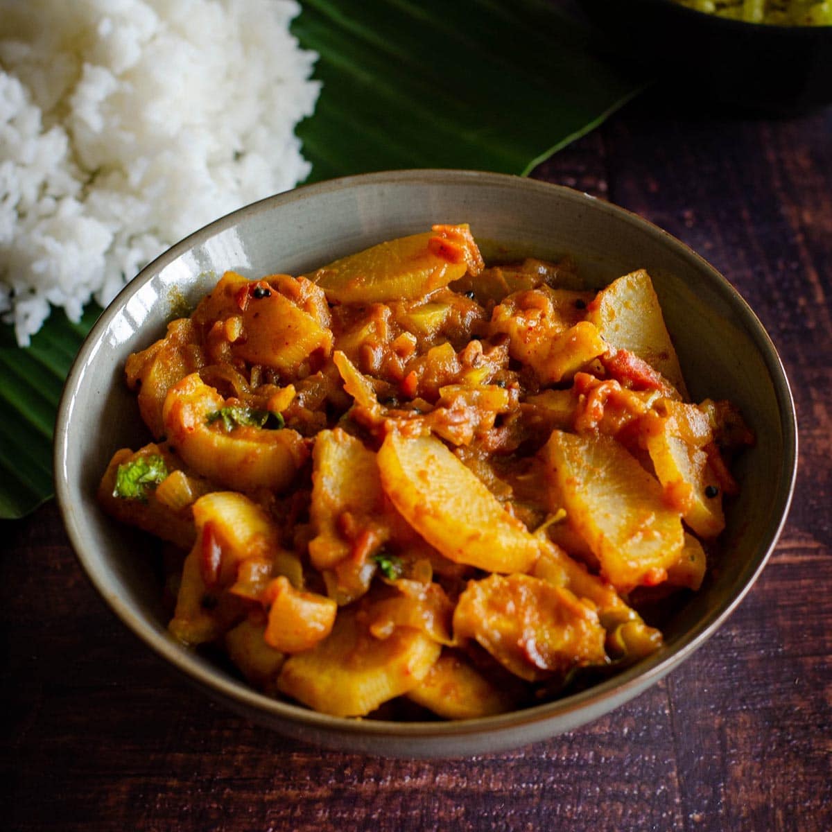 Mullangi Thokku- Radish Masala served in a dull grey bowl placed on a wooden table