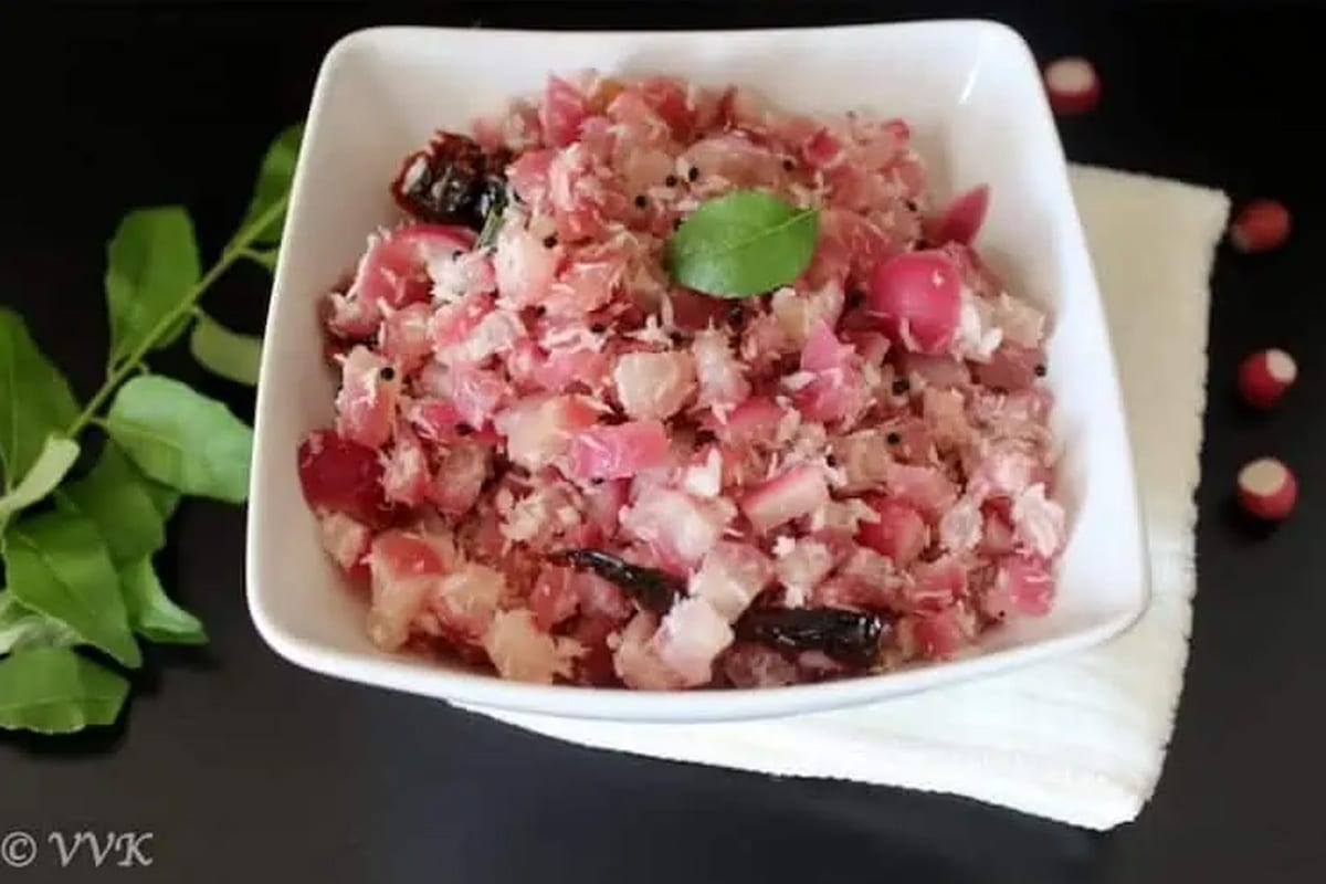 Red Radish Dry Curry served in a white bowl on a black surface with five raw radishes near the bowl