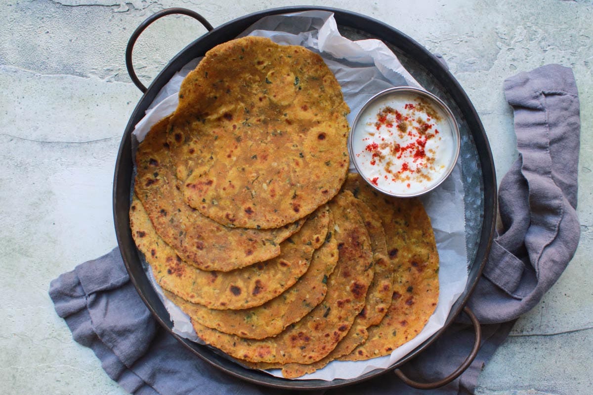 Zucchini and Paneer Parathas in a pan with yogurt on side