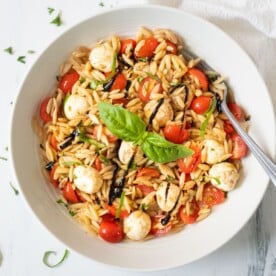 Caprese orzo pasta salad in a bowl garnished with basil leaves