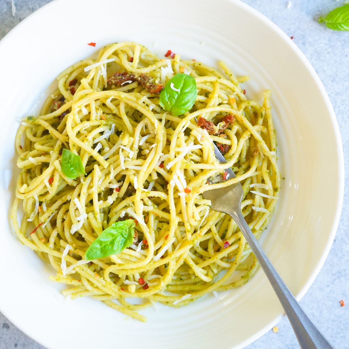 instant pot pesto pasta in a white bowl topped with basil leaves