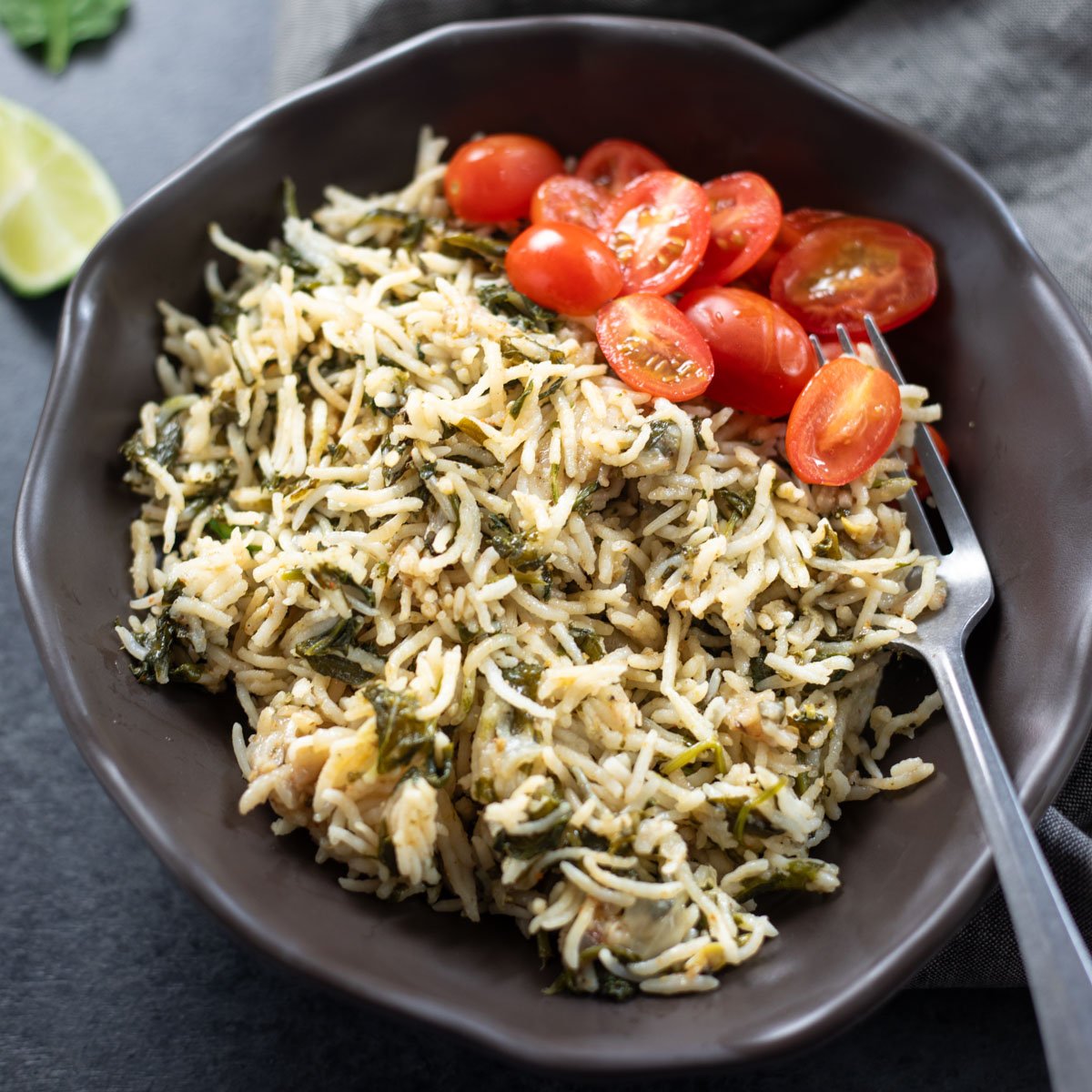 Insant pot spinach rice served in a bowl with tomatoes.