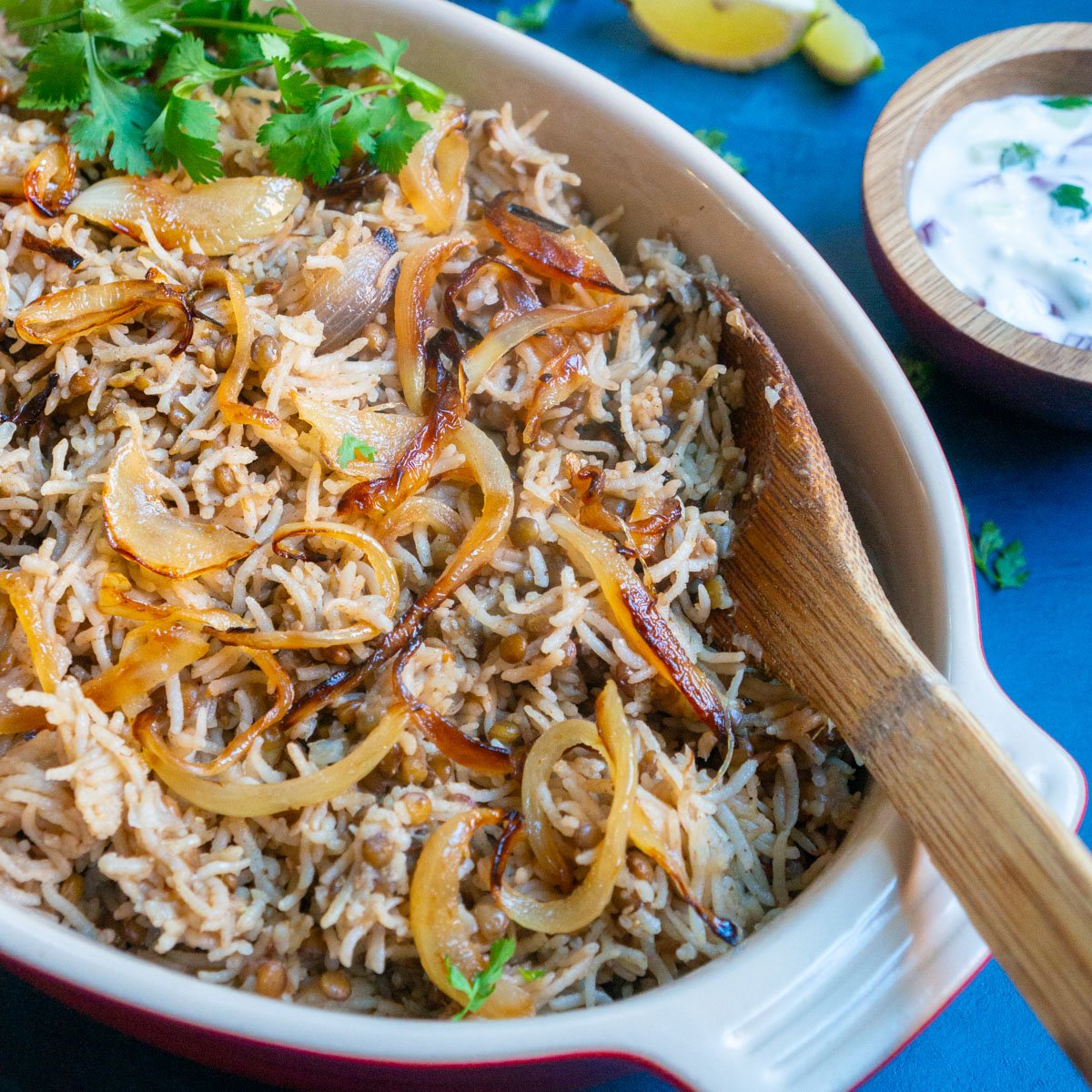 Instant Pot Lentils and Rice (Mujadara) in a serving platter with yogurt and lemon on the side.
