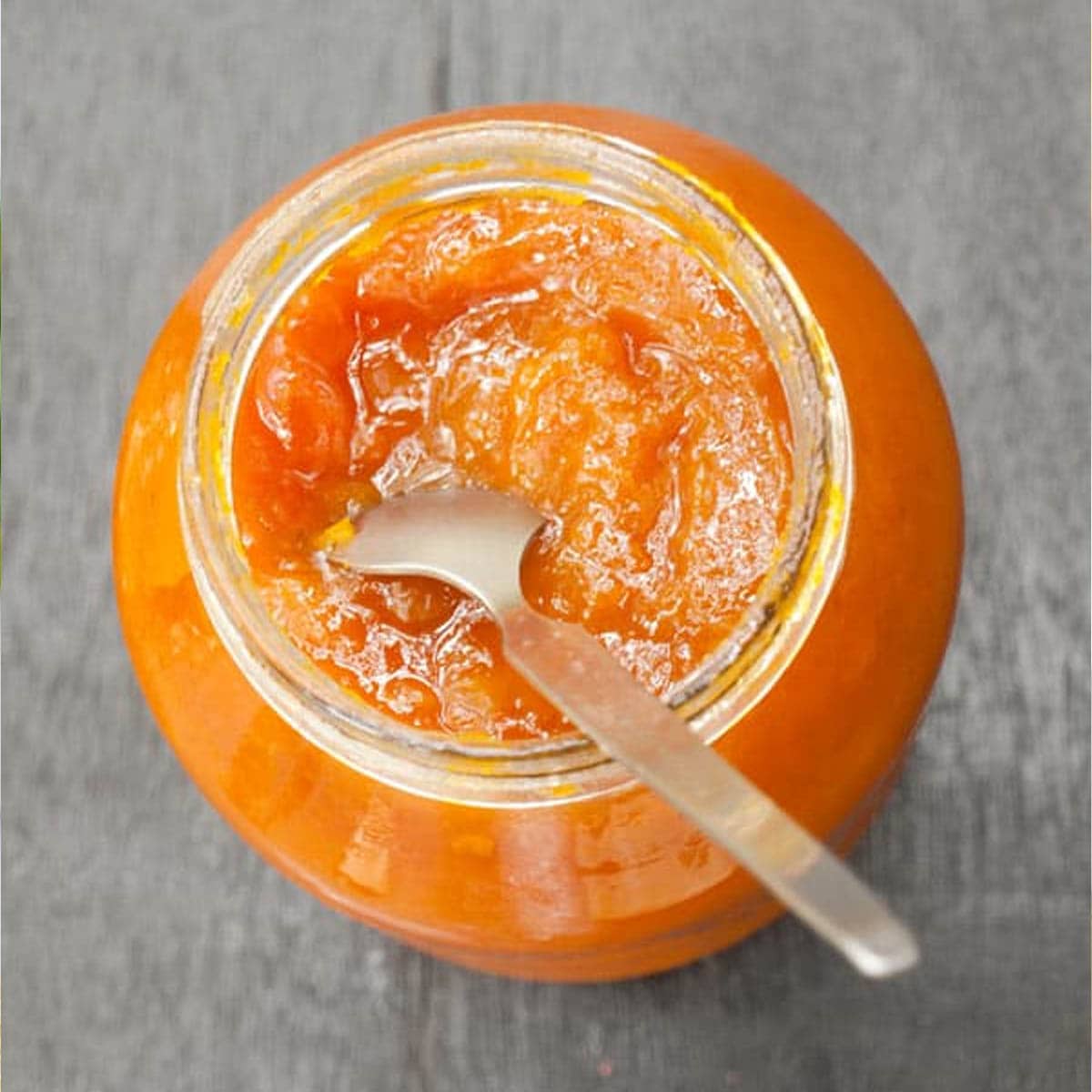 Mango jam in a glass jar with spoon