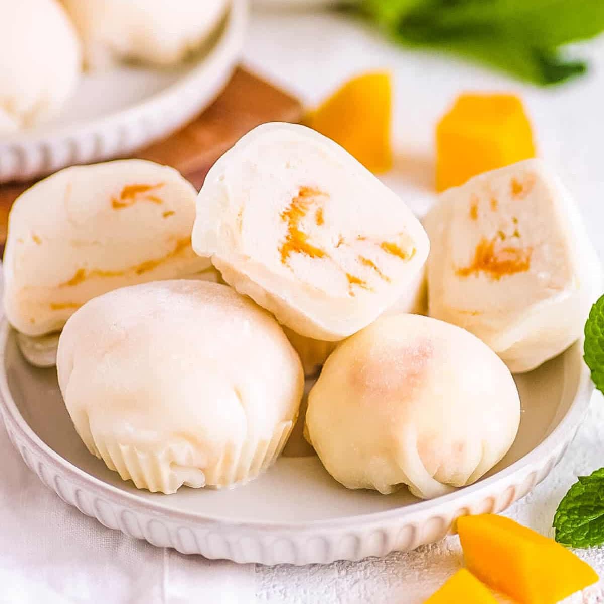 Mango mochi stacked on a white plate.