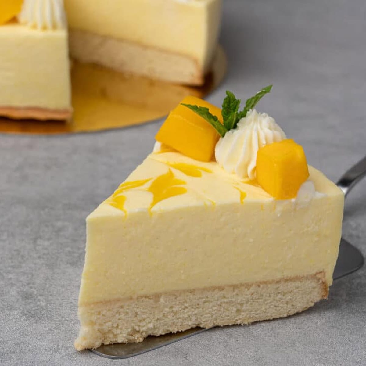 mango mousse cake with a slice against a grey background