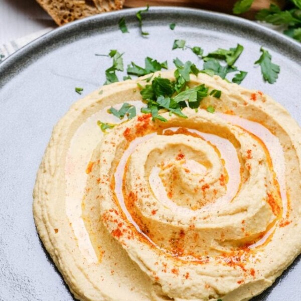Creamy Instant Pot hummus garnished with olive oil, chickpeas, and paprika, served with bread on the side